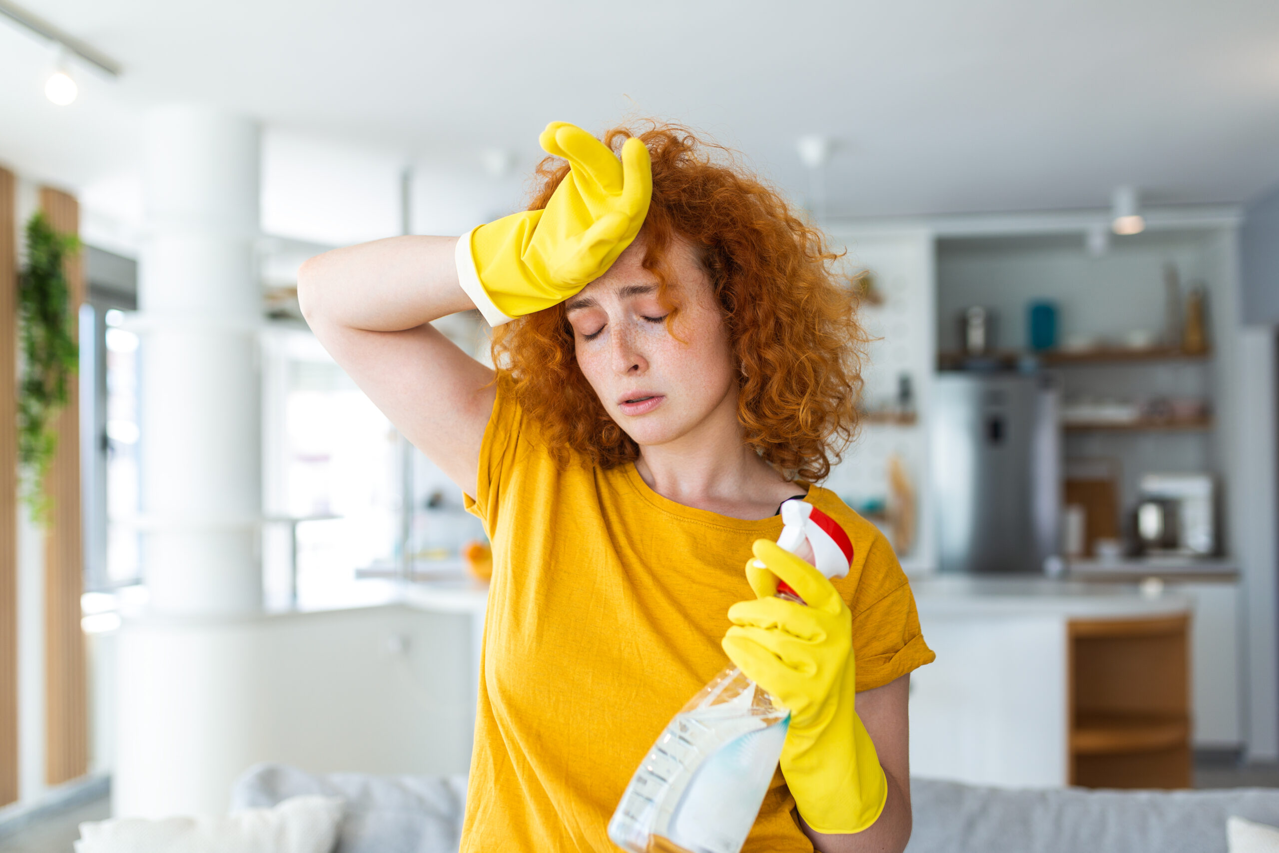 Portrait of young tired woman with rubber gloves resting after cleaning an apartment. Home, housekeeping concept.